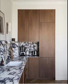 a kitchen with marble counter tops and wooden cabinets in the back drop off area, along with a white sink