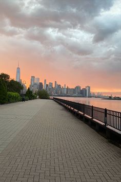 a bench sitting on the side of a brick road next to a body of water