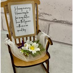 a wooden chair with a sign on it and flowers in the seat next to it