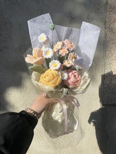 a person holding a bouquet of flowers in their hand on the sidewalk with sunlight coming through the window