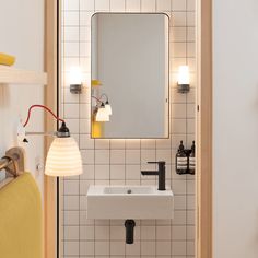 a bathroom with a sink, mirror and lights on the wall next to it's door