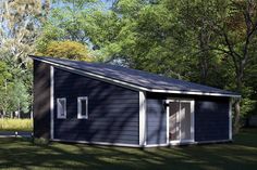 a small black shed sitting on top of a lush green field in front of trees