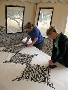 two women working on an intricately designed bedspread