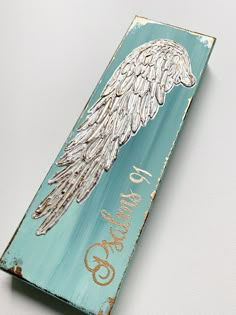 a wooden sign with an angel's wing painted on it