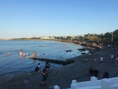 many people are standing on the beach near the water and in the water there is no one swimming