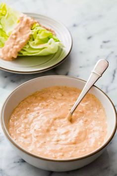 a bowl of dip next to a plate with lettuce