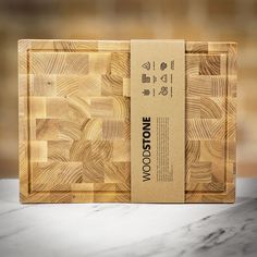 a wooden cutting board on a marble countertop with a cardboard box in the middle