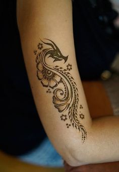 a woman's arm with a hendike tattoo on it, sitting down