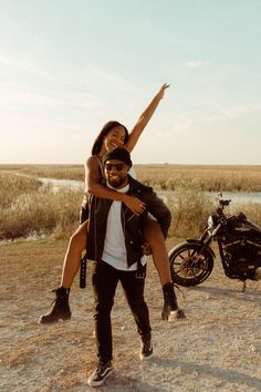 a man carrying a woman on his back while standing next to a motorbike