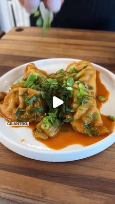 a white plate topped with dumplings covered in sauce