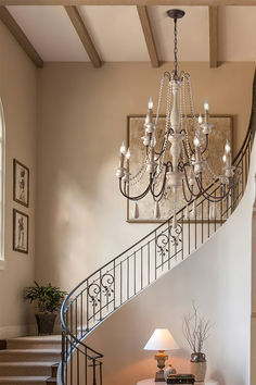 a chandelier hanging from the side of a stair case next to a table