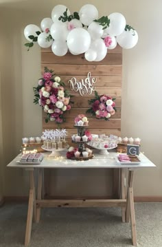 a table topped with lots of desserts and balloons on top of wooden planks