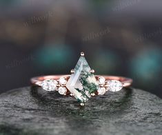 a green and white diamond ring on top of a rock