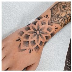 a person's hand with a black and white tattoo design on the left arm