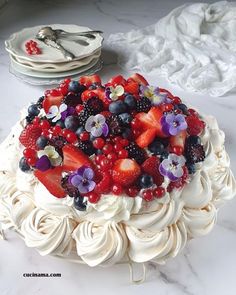 a cake with berries, blueberries and strawberries on it sitting on a table