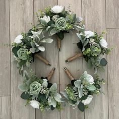 an overhead view of a wreath with flowers and greenery on a wooden floor,