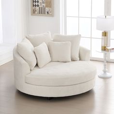 a living room with a white couch and round chair next to a lamp on the floor