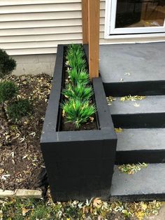 a planter with green plants in it sitting on the side of a house steps