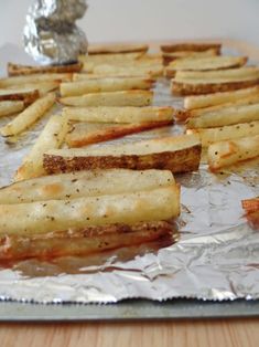 some french fries are sitting on tin foil and ready to be cooked in the oven