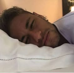 a close up of a person laying in a bed with white sheets and pillow cases