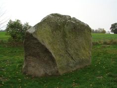 a large rock sitting on top of a lush green field