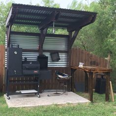 an outdoor bbq with grill and table in the back yard next to a fence