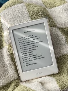 a kindle sitting on top of a blanket covered in a green and white checkered blanket