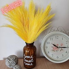 there is a vase with some yellow feathers next to a clock and two seashells