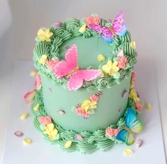 there is a green cake with butterflies on the top and bottom, sitting on a white surface