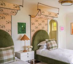 two beds in a bedroom with green headboards and plaid pillows on top of them