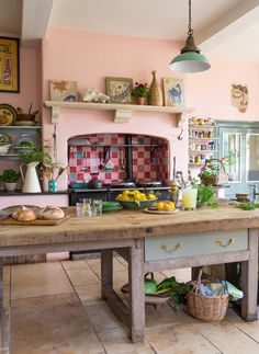 a kitchen with pink walls and an island in the middle, surrounded by potted plants