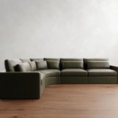 a large sectional couch sitting on top of a wooden floor next to a white wall