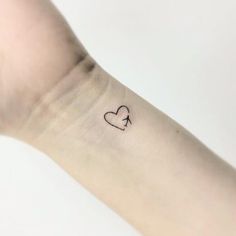 a small heart tattoo on the left inner arm, with an arrow in the middle