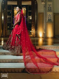 a woman in a red bridal gown standing on some steps