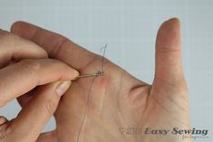 someone is sewing something on their fingers with the help of a needle in front of them