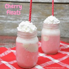 two mason jars filled with whipped cream and cherry floaties on a red checkered tablecloth