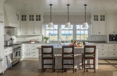 a kitchen with white cabinets and an island in the middle, along with three chairs