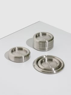 three stainless steel plates sitting on top of a white countertop next to each other