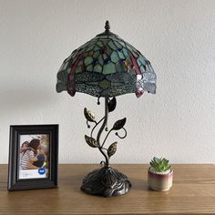 a lamp sitting on top of a wooden table next to a small potted plant