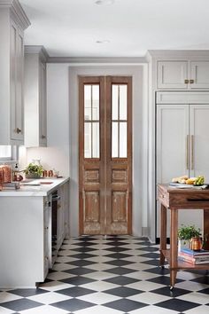 a black and white checkered floor in a kitchen with two doors leading to another room