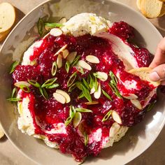 a bowl filled with mashed potatoes covered in cranberry sauce and topped with almonds