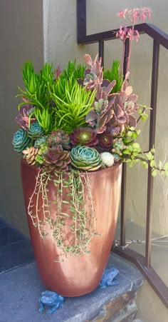 a large potted plant sitting on top of a stone step next to a metal railing