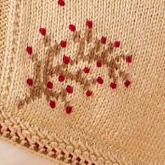 a close up of a knitted blanket with red dots on the bottom and side