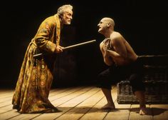 an image of two men on stage one is holding a stick and the other is kneeling down