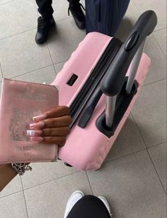 a person holding a pink piece of luggage in front of their feet and hand on top of it