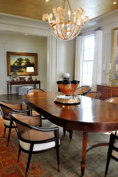 a dining room table with chairs and a bowl on it's centerpiece in front of a window