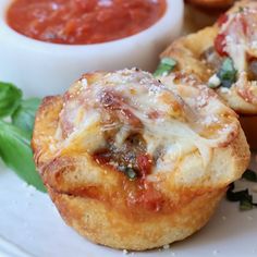 two mini pizzas on a white plate with sauce and basil sprinkled on top