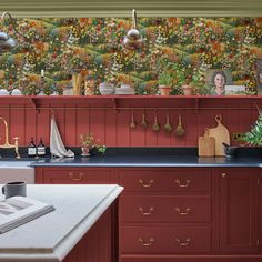 an image of a kitchen setting with red cabinets and floral wallpaper on the walls