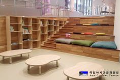 the interior of a book store with wooden shelves and tables in front of bookshelves