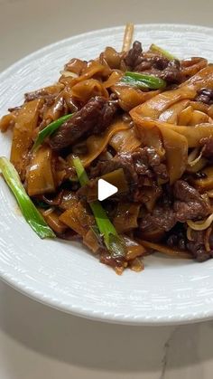 a white plate topped with beef and noodles